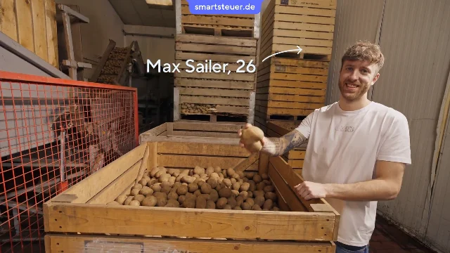 Video Thumbnail: Max Sailer steht vor einer Kartoffelkiste und hält eine herzförmige Kartoffel in die Kamera